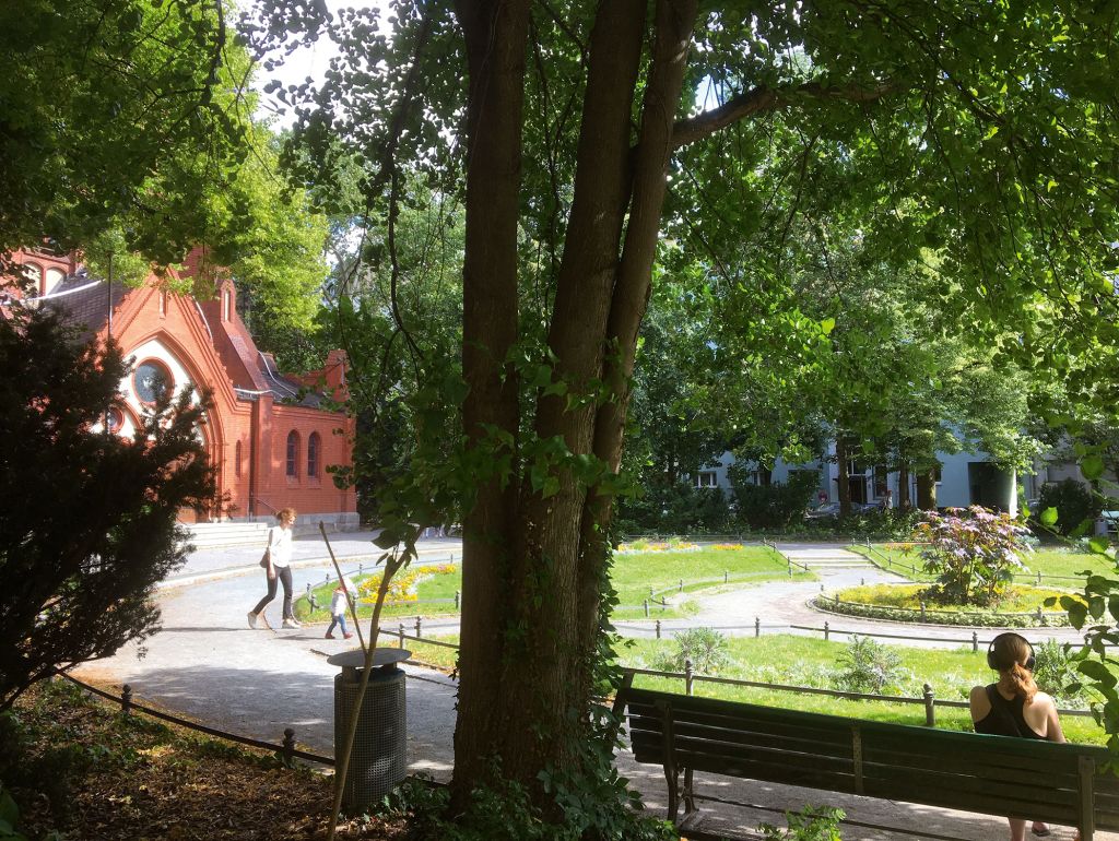 blick auf den ludwigkirchplatz eine frau mit kind grünflächen eine frau auf einer bank