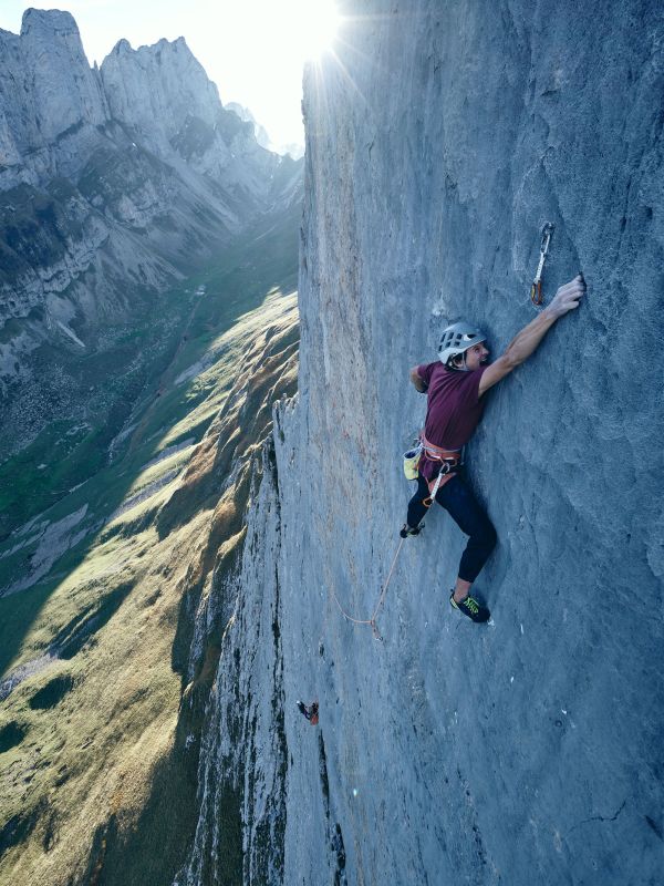 Ein Mann hägnt weit oben an einer steilen Felswand