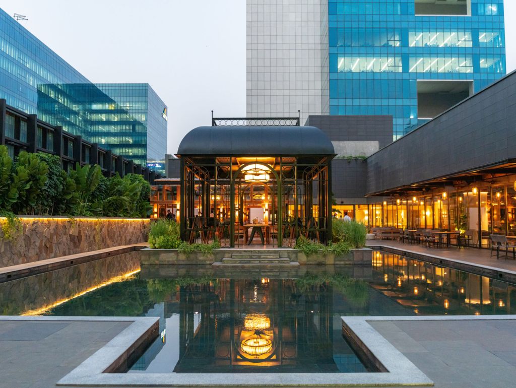 Ein Schwimmbecken im The Quorum in Hyderabad mit einem verglasten Hochhaus im Hintergrund