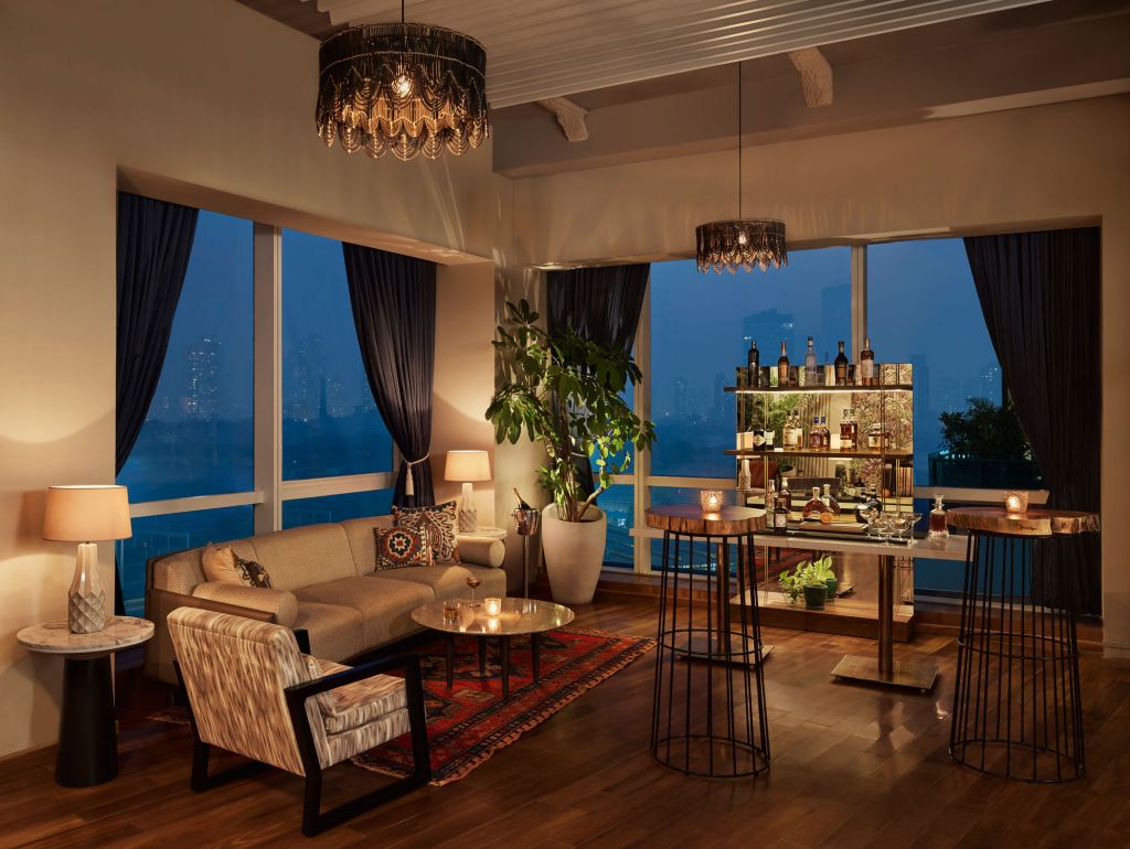 Ein Appartment-Wohnzimmer mit einer Bar und Blick auf die Stadt im The Quorum, Mumbai